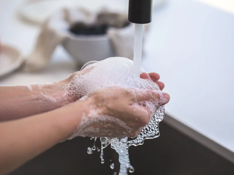 Nahaufnahme von Händen, die mit Schaum unter dem Wasserhahn gewaschen werden, Sinnbild für einen Waschzwang